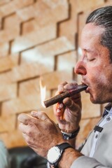 Mid adult man lighting and smoking a cigar in a tobacco factory