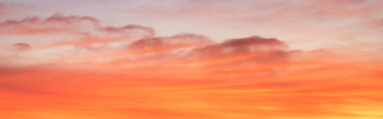 Beautiful and elegant gradient orange-gold clouds with sunlight on a blue sky, perfect for a background. Amazing view of bright orange and red sunset clouds floating above the shadows .