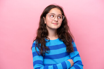 Fototapeta premium Little girl isolated on pink background With glasses and thinking while looking up
