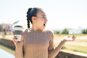 Young moroccan girl holding a take away coffee at outdoors with surprise facial expression