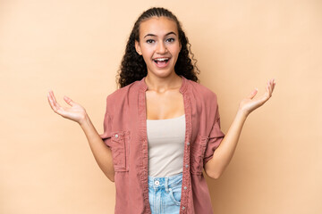 Young woman isolated on beige background with shocked facial expression