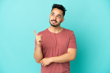 Fototapeta premium Young caucasian man isolated on blue background pointing up a great idea