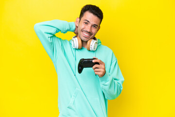 Young handsome man playing with a video game controller over isolated wall laughing © luismolinero