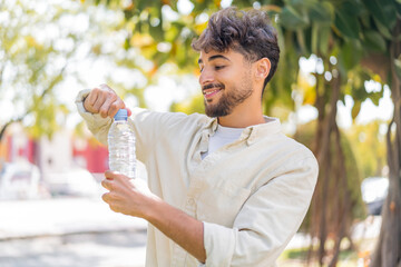 Young Arabian handsome man with a bottle of water at outdoors