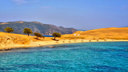 Greek sandy beach with trees and beautiful blue sea water