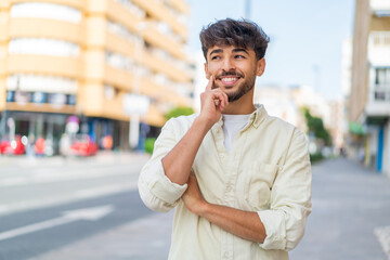 Young Arabian handsome man at outdoors thinking an idea while looking up