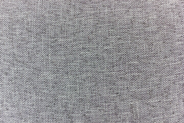 Close up shot captures the detailed woven texture of a grey fabric. The material exhibits a fine, consistent pattern of interlocked threads, creating a subtle yet tactile surface.