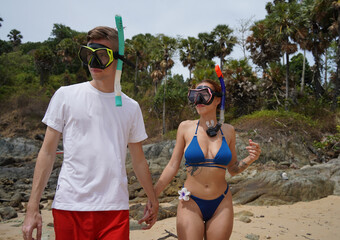 A man and woman wear goggles and snorkels before diving