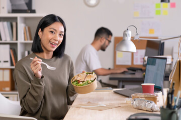 Asian woman eating healthy meal while working, Businesswoman having a lunch break at the office