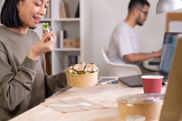 Asian woman eating healthy meal while working, Businesswoman having a lunch break at the office