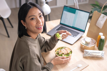 Asian woman eating healthy meal while working, Businesswoman having a lunch break at the office