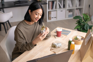 Asian woman eating healthy meal while working, Businesswoman having a lunch break at the office