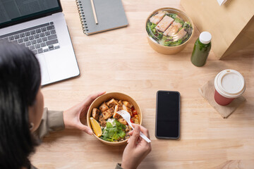 Asian woman eating healthy meal while working, Businesswoman having a lunch break at the office