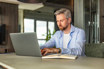 Young businessman sitting at a table at home working on a laptop