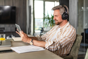 Confident man wearing headset speaking and watching business webinar training, listening to lecture.