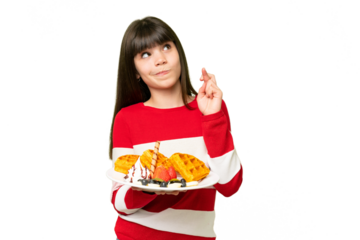 Little girl holding waffles over isolated chroma key background with fingers crossing and wishing the best