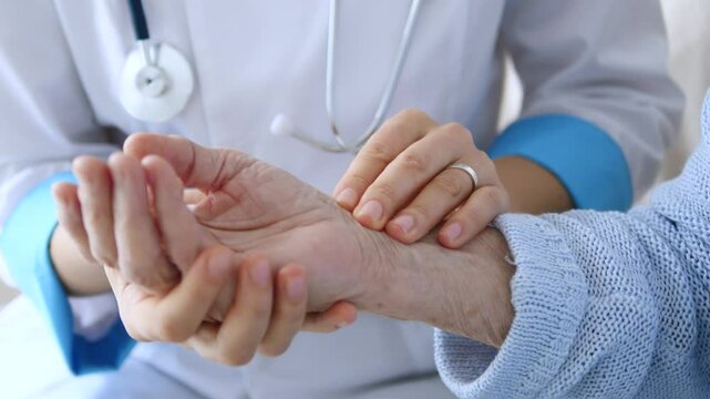Medical professional carefully checking elderly patient's wrist during routine health assessment, gently palpating radial pulse and evaluating circulatory wellness with professional compassion