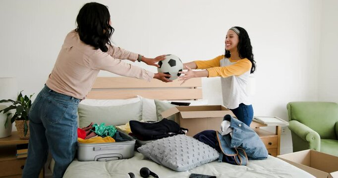 Opening suitcase Diverse mother and teen daughter packing items into moving box at home before move