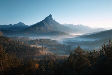 Fototapeta premium A breathtaking mountain landscape bathed in the golden hues of sunrise, enveloped in tranquil morning mist. The serene composition and soft atmospheric light evoke a sense of peace and natural harmony