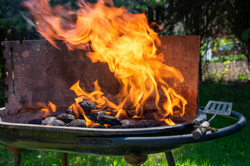 Charcoal burning in a grill with visible orange flames and black coals, high heat for barbecue cooking.