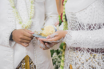 Bride and groom exchanging rings during a traditional Indonesian wedding ceremony, symbolizing their commitment and love. Asian muslim wedding	
