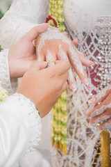 Bride and groom exchanging rings during a traditional Indonesian wedding ceremony, symbolizing their commitment and love. Asian muslim wedding	
