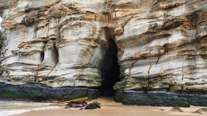 Ghosties Beach Caves NSW Australia.Coastal rock formations with cave entrance at low tide along a serene beach