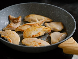 Slices of chicken breast cooking in a frying pan