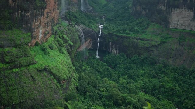 4K shot of Devkund waterfall as seen from Savlya Ghat View Point at Tamhini Ghat near Pune in Maharashtra, India. Scenic view of Devkund waterfall from a mountain. Natural monsoon background in India.