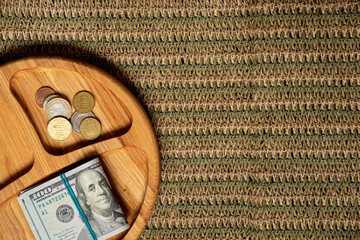 Wooden plate with dollars and coins on knitted background, finance, profit, savings