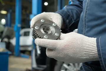 Car service and new auto parts. Camshaft gear. Close-up. An auto mechanic inspects and monitors the...