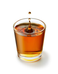 Drop falling into glass of whiskey or tequila creating splash on white background, capturing moment of impact and ripple effect