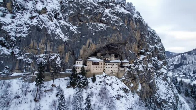 Ostrog Monastery nestled in a cave of a mountain, in winter, covered with snow