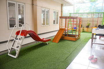 Set of different cute toys in children's playground. Preschool building exterior with playground and toys on a sunny day