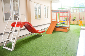 Set of different cute toys in children's playground. Preschool building exterior with playground and toys on a sunny day