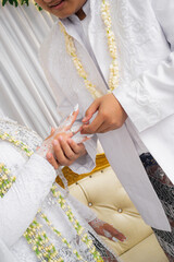 Bride and groom exchanging rings during a traditional Indonesian wedding ceremony, symbolizing their commitment and love. Asian muslim wedding