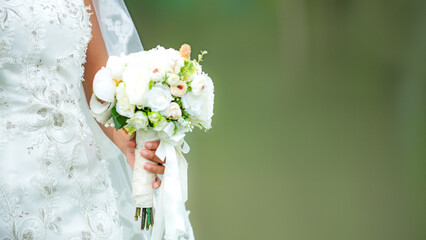 Bride holds edding bouquet. Bride wedding white dress in the garden. Nature green Background