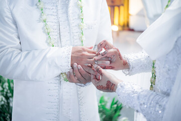 Bride and groom exchanging rings during a traditional Indonesian wedding ceremony, symbolizing their commitment and love. Asian muslim wedding