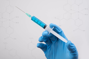 A hand wearing a blue glove holds a syringe against a background of chemical structures,...