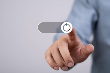 A person reaching to touch a power button on a digital interface, symbolizing activation or control in technology.