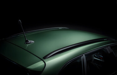 Close-up view of a green car roof with black matte antenna and textured plastic trim under studio lighting, isolated against a dark background for advertising, branding or design templates