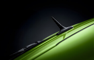 Close-up view of a green car roof with black matte antenna and textured plastic trim under studio lighting, isolated against a dark background for advertising, branding or design templates