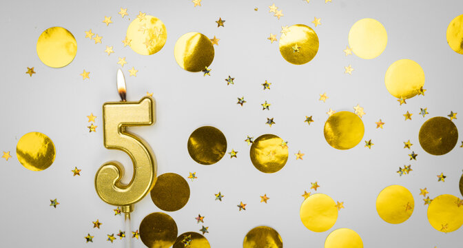 Burning Birthday candle number 5 on white background with golden confetti and glitter. Five years old. Happy Birthday. Card on festive background.