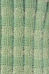 A macro detail of green knitted fabric with a unique texture and protruding plastic threads