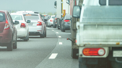A busy highway with a truck in the middle of the traffic. The truck is in the middle of the road and is surrounded by other cars. The traffic is heavy and the cars are moving slowly