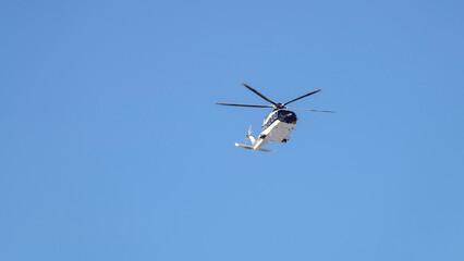A white helicopter on a blue sky background, a passenger helicopter in good clear weather on a sunny day. Aerial helicopter tour of the territory from a height