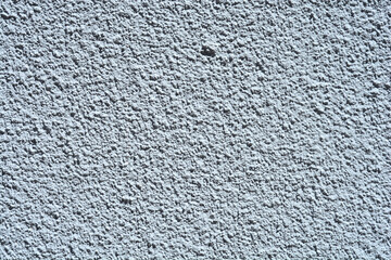 A close-up texture of a rough, grainy facade or wall in a grey color