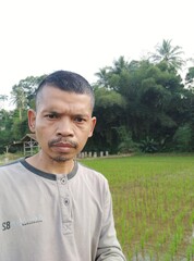 Portrait of a Man Standing in Front of a Rice Field in Rural Area