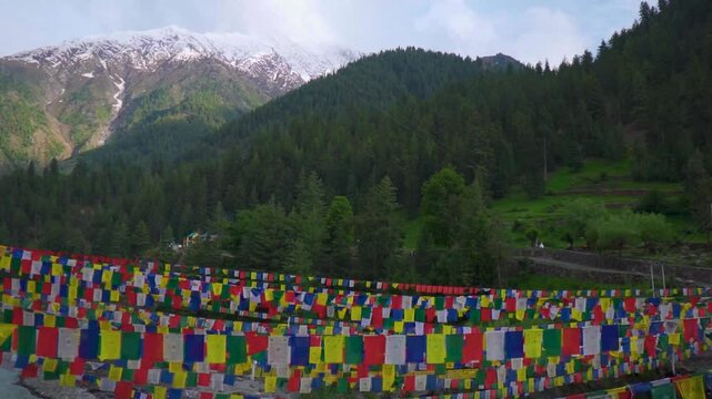 Colorful Buddhist prayer flags in front of the snowy Himalayan mountain peaks during a sunny day as seen on the way towards Triloknath temple in Pattan valley, Lahaul district, Himachal, India.