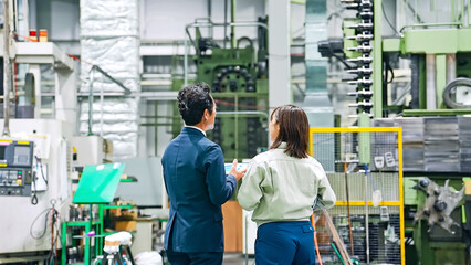 工場を視察する男性ビジネスパーソンと女性作業員
